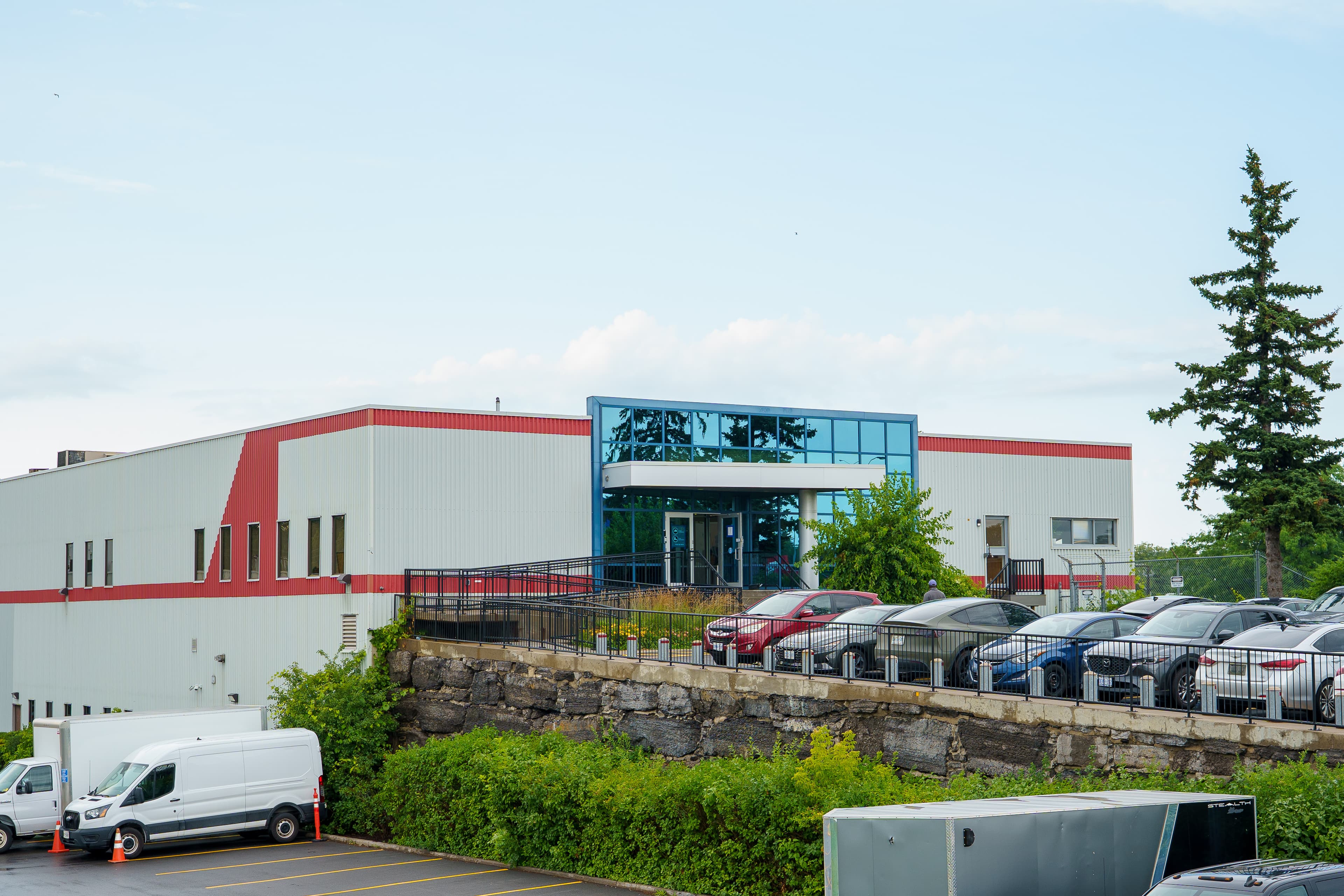 The Queensview building on a summer morning, its blue glass entrance above the parking lot
