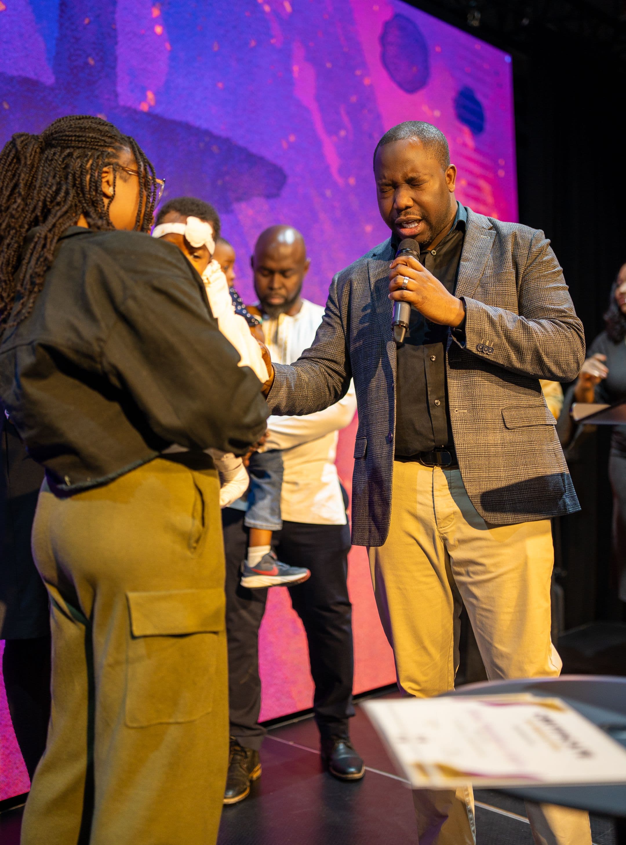 A pastor praying over a family as they dedicate their child